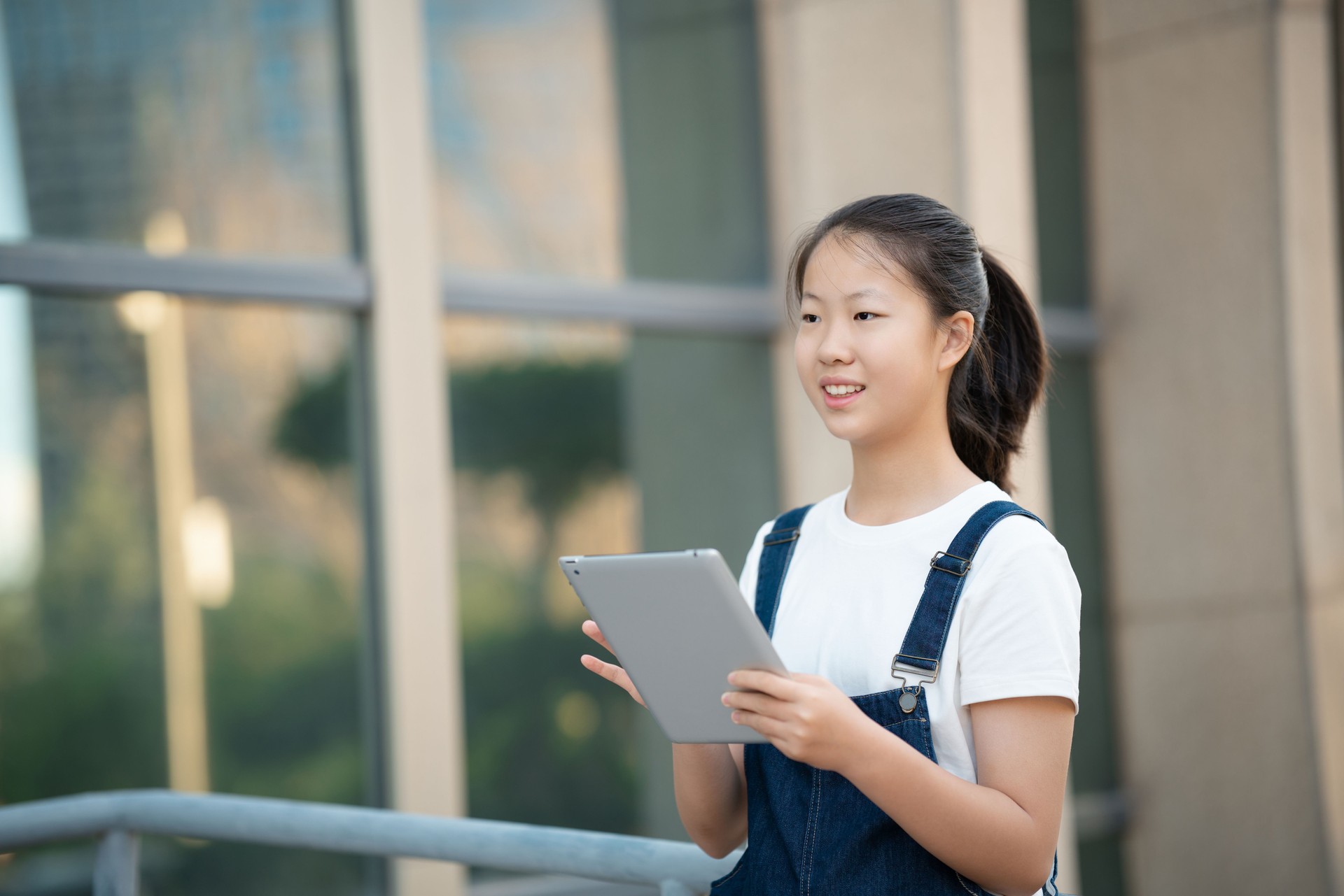 Teenage girl using digital tablet on middle school campus